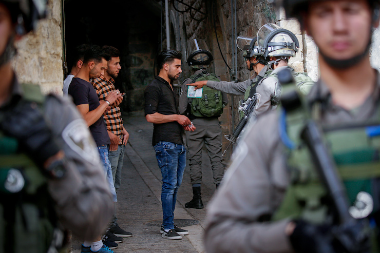 Israeli soldiers check the IDs of Palestinian boys in the Old City of Hebron, West Bank, on May 23, 2018. (Wisam Hashlamoun/Flash90)