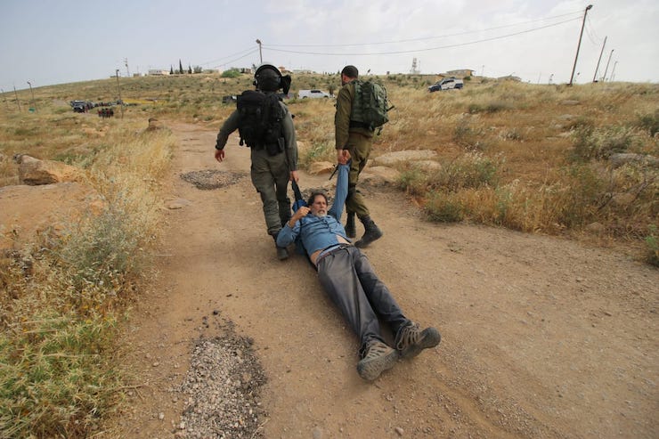 Israeli soldiers violently drag Rabbi Arik Ascherman while he and a group of activists attempt to repair an access road for a cluster of Palestinian villages in the South Hebron Hills on May 3, 2019. (Ahmad al-Bazz/Activestills.org)