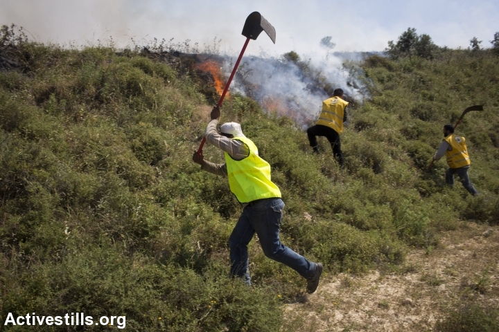Palestinian fire fighters try to extinguish a fire that was set by Israeli settlers, during an attack by Israeli settlers on the West Bank village of Asira al Qibliya, April 30, 2013. (Oren Ziv/Activestills.org)