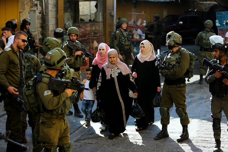 Israeli security forces guard as Jewish Israelis tour the Palestinian side of the old city market in the West Bank city of Hebron, June 15, 2019. (Wisam Hashlamoun/Flash90)