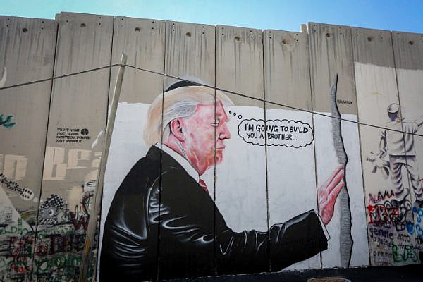 A mural depicting President Donald Trump kissing an Israeli army watchtower is seen on the separation barrier in the West Bank city of Bethlehem, August 4, 2017. (Flash90)