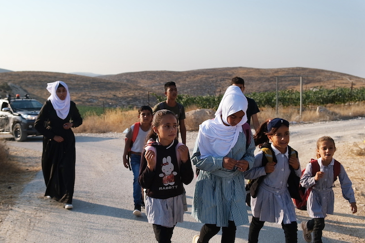 Students from the Palestinian village of A-Tuba in the South Hebron Hills walk to school as the Israeli army escorts them to protect them from settler violence. (Rachel Shor)