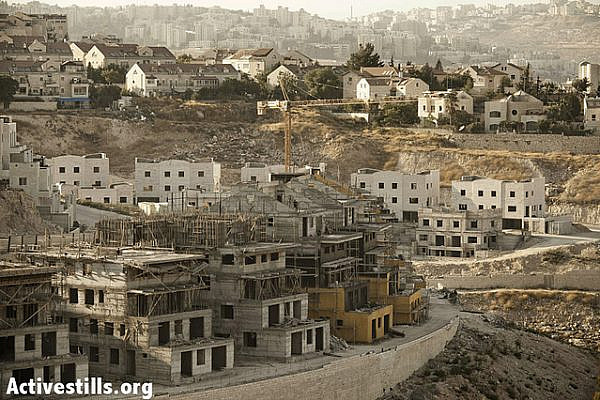 Ongoing construction work in the Pisgat Ze'ev settlement in East Jerusalem, as seen from the Anata neighborhood on August 29, 2012. Under international law, all of the new Jewish neighborhood established by Israel after 1967 are deemed to be illegal and supposedly to be "removed" as a prelude to a peace agreement. In the meantime, residents of Anata complain of having lost a lot of land and access to the hill on which this neighborhood of Pisgat Ze'ev is built, although they add that several local families have actually moved to the settlement in order to find themselves on the right side of the Separation Wall, and avoid having to go through a checkpoint several times a day. (photo: JC/Activestills.org)