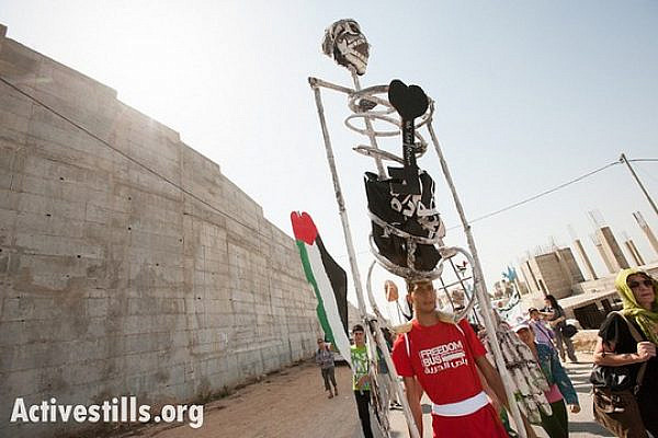 Carrying giant puppets, Palestinians of Al-Walaja, together with Palestinian, international, and Israeli supporters organized by the Freedom Bus campaign march through the West Bank village of Al-Walaja to protest the Israeli separation wall, September 28, 2012. (photo: Ryan Rodrick Beiler/Activestills.org)