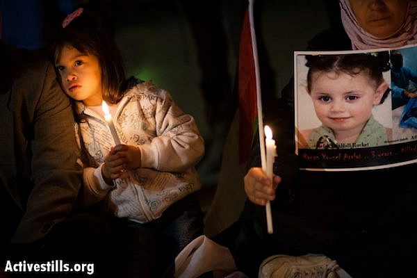 A girl holds a candle next to a photo of 3-year-old Ranan Yousef Arafat, who was killed by Israeli airstrikes in Gaza, as Palestinians gathered in Bethlehem's Manger Square to mourn the victims of Israeli military strikes and to call for an end to the escalation of violence, November 17, 2012.