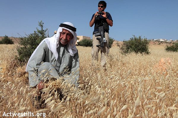 A Palestinian farmer is filmed by an Israeli settler in the village of Tuqu', close to the settlement of Teqoa, West Bank, May 25, 2012. (photo: Activestills)