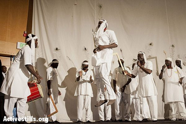 Member of a dance group of Sudanese refugees from the Darfur region dressed with traditional costumes dance on stage as part of a cultural festival of the Sudanese community at a cultural centre in south Tel Aviv on February 15, 2013. (Shiraz Grinbaum/Activestills.org)