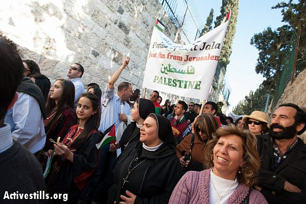 In the annual Palm Sunday procession, Palestinian Christians carry signs naming their West Bank communities, all of which are cut off from Jerusalem by the Israeli separation barrier, requiring their residents to obtain special permits to enter, March 24, 2013. Such restrictions have dramatically reduced the number of Palestinians able to participate in religious traditions of any faith in Jerusalem.