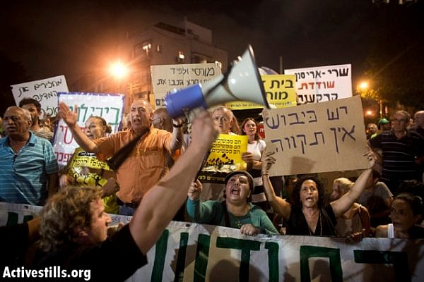 Demonstrators holding anti-Capitalist and anti-occupation signs (Oren Ziv / Activestills)