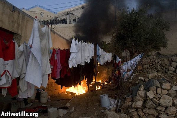 A Palestinian house burns after it was set on fire by settlers in the West Bank city of Hebron during the eviction of Jewish settlers from a disputed building. December 4, 2008 (Activestills.org)