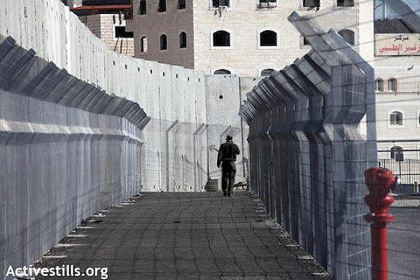 A man walks toward the checkpoint at the entrance of Shuafat Refugee Camp in East Jerusalem, December 27, 2011 (Anne Paq/Activestills.org)