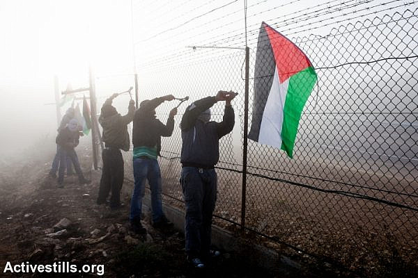 Palestinian activists cut part of the Separation Barrier in the West Bank village of Rafat, near Ramallah, November 15, 2013. (photo: Activestills.org)