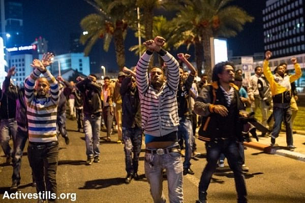 Asylum seekers with hands crossed in the air on streets of Tel Aviv (Yotam Ronen / Activestills)