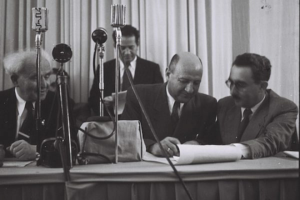 Eliezer Kaplan, with Moshe Shertok and David Ben-Gurion looking on and Zeev Sharef standing behind them, sign the Declaration of Independence at the Museum in Tel Aviv. (Zoltan Kluger/GPO)