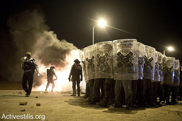 Israeli policemen advance as Bedouin youth throw stones during a protest against the Israeli government's Prawer Plan, near the town of Hura, Israel, on November 30, 2013 near the town of Hura, Israel. (Oren Ziv/Activestills.org)
