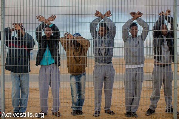 African asylum seekers jailed in Holot detention center protest behind the prison's fence, as other asylum seekers take part in a protest outside the facility, in Israel's southern Negev desert, February 17, 2014.