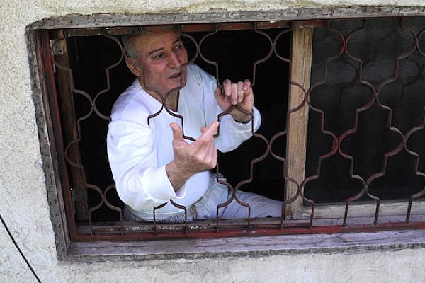Ismail Shawa standing in the window he is forced to climb through in order to exit and enter his Jaffa home. (Photo by Yudit Ilany)