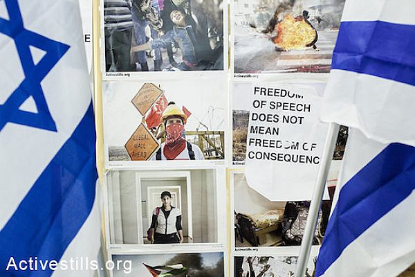 A slogan covering Activestills photos between two Israeli flags placed by nationalist students as a response to the exhibition. The students protested "un equal representation of the conflict", in their words, during a conference titled "Visual Culture Between Obedience and Resistance", Ramat Gan, Israel, March 30, 2014. (Shiraz Grinbaum/Activestills.org)