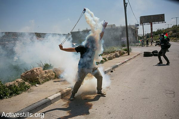 A Palestinian protester throws a gas canister back at Israeli police near the Israeli Ofer military prison in West Bank town of Betunia on April 4, 2014. The protest was calling on the the release of Palestinian political prisoners, including those who Israeli was supposed to release this month, as part of the Israeli Palestinian negotiations. (photo: Activestills.org)