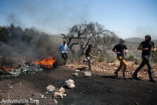 Demonstrators set fire during the weekly protest against the occupation in the West Bank village of Kafr Qaddum, May 2, 2014.
