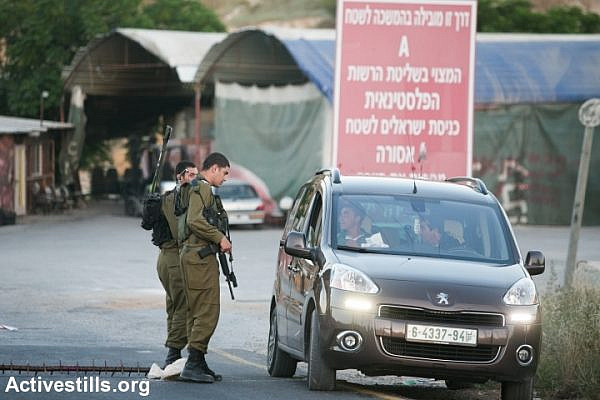 Israeli soldiers stop Palestinians at a flying check-point at the entrance to the West Bank city of Hebron, seen on June 15, 2014. A complete closure was put on the city after three Israeli teenagers went missing near a West Bank settlement. The three, all students at a Jewish seminary, went missing late on June 12 as they were hitchhiking between Bethlehem and Hebron and are believed to have been kidnapped. (Photo by Yotam Ronen/Activestills.org)