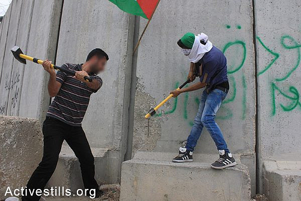 Palestinian activists try to destroy parts of the separation wall during the 'Return March near Tulkarem, West Bank, May 31, 2014. The marchers attempted to cross the barrier while chanting the names of their destroyed villages and towns located inside Israel. (photo: Activestills)