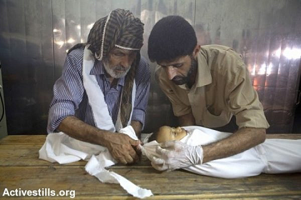 Palestinians prepare the body of a baby in Kamal Edwan Hospital's morgue after an attack on Beit Hanoun elementary school killed at least 17 people, Jabalyia, Gaza Strip, July 24. The school was being used as a shelter by 800 people at the time (photo: Anne Paq/Activestills)