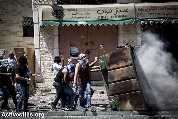 Palestinian youths taking cover during clashes that broke out in East Jerusalem following the suspected kidnapping and murder of a Palestinian teenager, East Jerusalem, July 2, 2014. (Photo by Oren Ziv/Activestills.org)