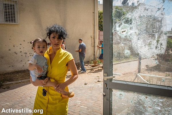 Woman near shattered window caused by a Hamas rocket on July 15, 2014 in the town of Sderot, Israel. (Photo by Activestills.org)