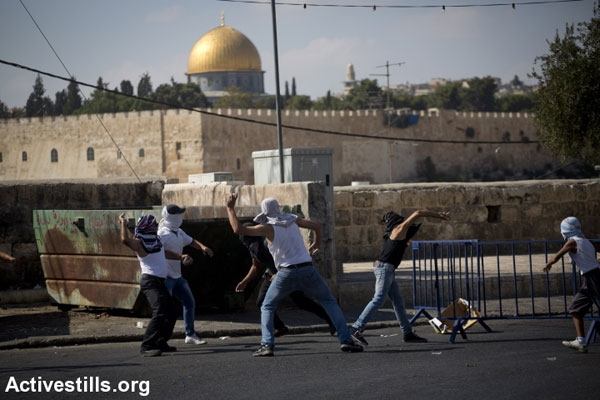 Palestinian youth throw stones during clashes in the East Jerusalem neighborhood of Ras al Amud, with the Aqsa Mosque seen in the background. (Photo by Oren Ziv/Activestills.org)