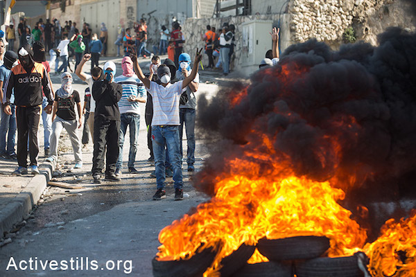 Palestinian youth burning tires during clashes with Israeli police in the East Jerusalem neighborhood of Issawiya on October 24, 2014. (Activestills.org)