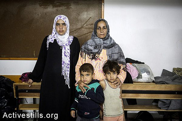 Majda Bashir with three of her children, stand in the classroom where she stays with her family in the UNRWA al Mazra'a preparatory girls school, in the city of Deir al-Balah, eastern Gaza Strip, November 7, 2014. According to Majda, her family does not receive any food aid because the government was late to register the destruction of their home, preventing them to get on the list of beneficiaries. Several of her children suffer from malnutrition. Around 1,400 displaced Palestinians live in the school in very precarious conditions. Anne Paq/Activestills.org