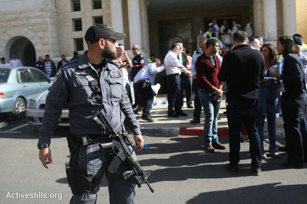 An Israeli police officer stands outside the Jerusalem synagogue where two Palestinians killed four worshippers and seriously wounded seven others, November 18, 2014. (Photo by Oren Ziv/Activestills.org)