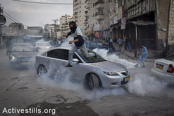 A Palestinian runs to take cover from tear gas, during clashes with Israeli police at the Palestinian refugee camp of Shuafat in East Jerusalem, November 5, 2014. Clashes broke after a Palestinian man drove a car into a crowd, killing a policeman and injuring 13 people in Jerusalem. By: Oren Ziv/Activestills.org