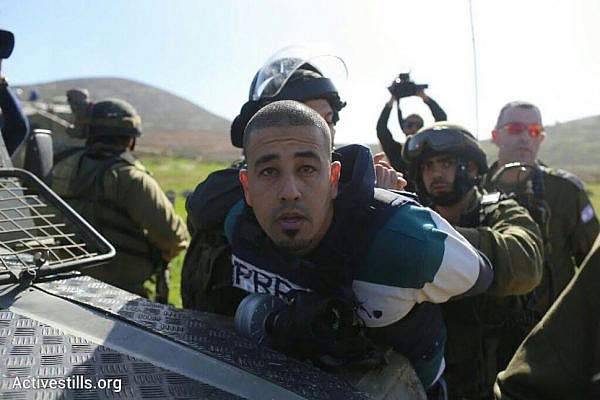 Israeli soldiers arrest a Palestinian journalist during clashes near the illegal West Bank outpost of Adei Ad. (Activestills.org)