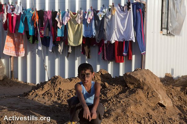 A Palestinian child with ash on his face sits in one of the newly established camps with metal caravan shelters for displaced people in the village of Khuza’a, eastern Gaza Strip, November 9, 2014. (photo: Activestills.org)