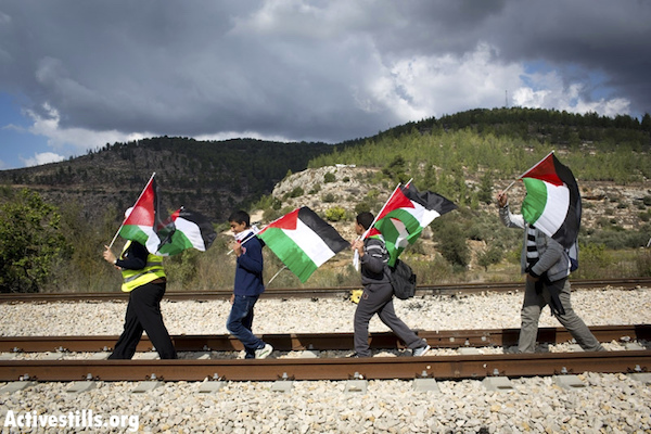 Palestinians march on the railway line connecting Tel Aviv and Jerusalem through the West Bank, during a protest against the plan to build the separation wall in the West Bank village of Battir, November 13, 2012. (Photo by Oren Ziv/Activestills.org)