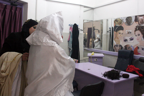 Haya Assad tries on her wedding dress in a Gaza City shop. (Photo by Abeer Ayyoub)