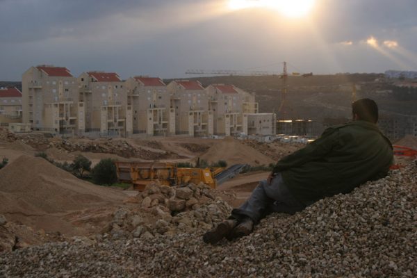 A Palestinian from the West Bank village of Bil'in looks out at the Modi'in Illit settlement bloc. (photo: Oren Ziv/Activestills.org)