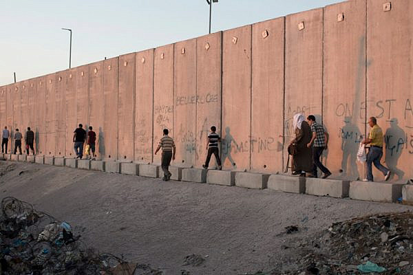 Palestinians walk along the separation wall in the West Bank. (Activestills.org)