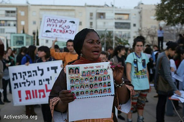 A woman holds up a photo of a refugee daycare center's yearbook during a protest against living conditions in south Tel Aviv, April 19, 2015. Five refugee children have recently died due to the substandard living conditions in daycare centers. (photo: Oren Ziv/Activestills.org)