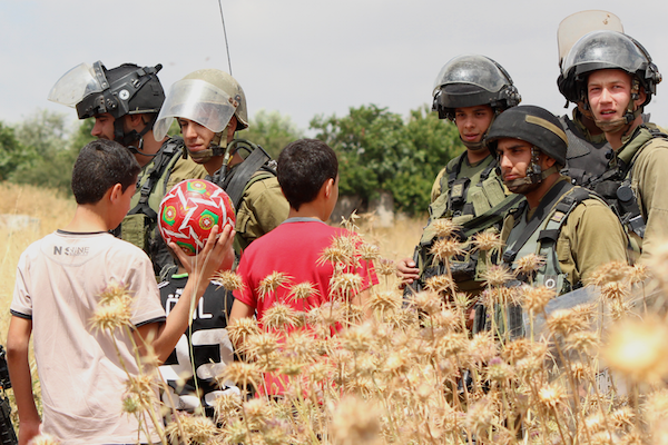Palestinian children with Israeli soldiers during the weekly demonstration in Nabi Saleh, May 29, 2015. (Natasha Roth)