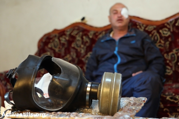 Palestinian photojournalist Nidal Ashtiyeh displays his gas mask at his home in the village of Salem, West Bank, May 16, 2015. A rubber bullet fired by Israeli troops at a Nakba Day protest near Nablus struck the glass of his mask, which shattered and wounded his eye. (Ahmad Al-Bazz/Activestills.org)