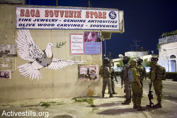 Israeli soldiers stand outside a souvenir shop for tourists in Bethlehem, July 12, 2014. (Activestills.org)
