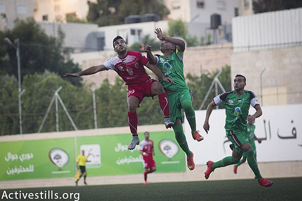 Gaza Strip's Shejaiya's player (green) vies with Hebron's Al-Ahly's player (red) during their return leg football match for the Palestine Cup final, August 14, 2015 at Hussein Bin Ali Stadium in the West Bank city of Hebron. 
Hebron's Al-Ahly won 2-1, in the first footballing showdown in 15 years with a team from Israeli-blockaded Gaza to be proclaimed Palestinian champions. Al-Ahly will now represent Palestine, a member of football's world governing body FIFA since 1998, in international competitions. (photo by: Oren Ziv / Activestills.org)