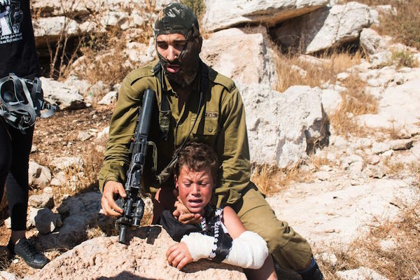 An Israeli soldier holding Mohammed Tamimi, 12, in a headlock during a demonstration in Nabi Saleh, August 28, 2015. (Karam Saleem)