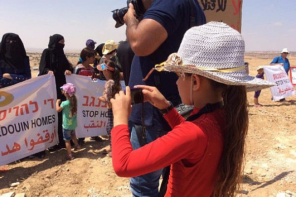 A Bedouin girl from Umm al-Hiran takes photos at a demonstration against the destruction of the village, August 27, 2015. (photo: Michal Rotem)