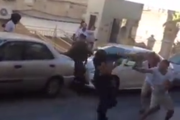 Screenshot of masked Israeli soldiers pepper spraying Palestinians detained at the Beit Hadassah checkpoint. (Courtesy of Youth Against Settlements)