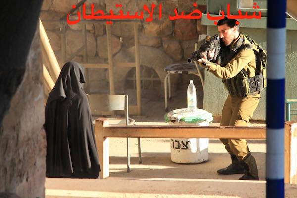 Hadeel al-Hashlamon stands frozen at the ‘Shoter’ checkpoint as soldiers train their weapons on her in downtown Hebron. (Photo courtesy of Youth Against Settlements)