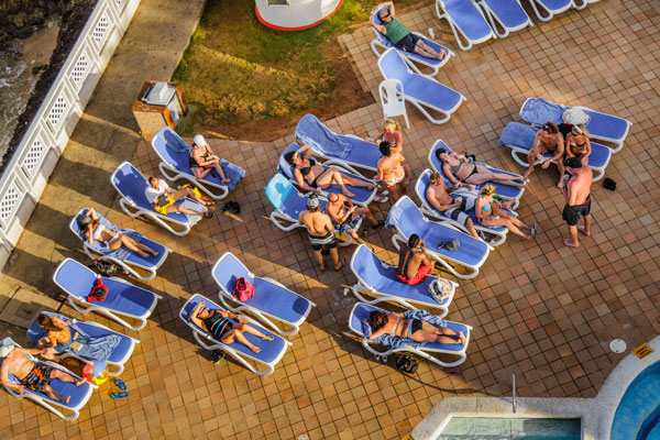 Illustrative photo of tourists sunbathing at a hotel pool. (Photo by Benoit Daoust/Shutterstock.com)